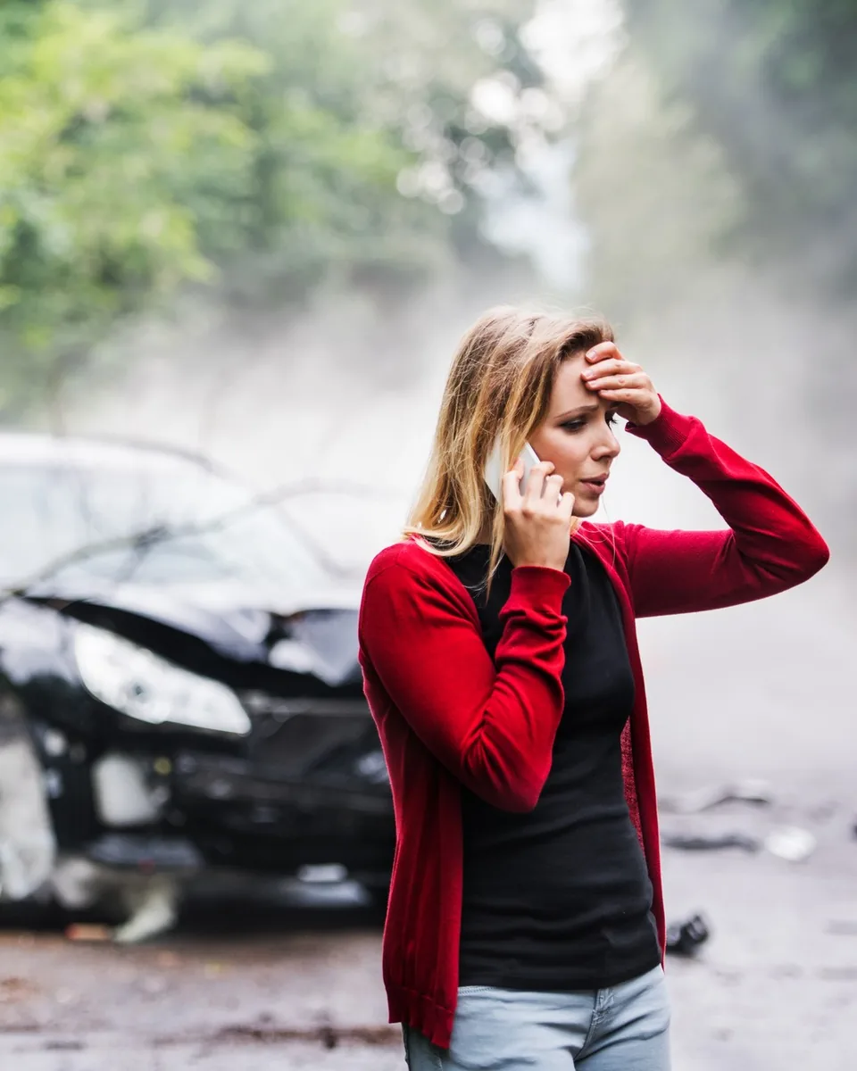 A woman on the phone beside her damaged car